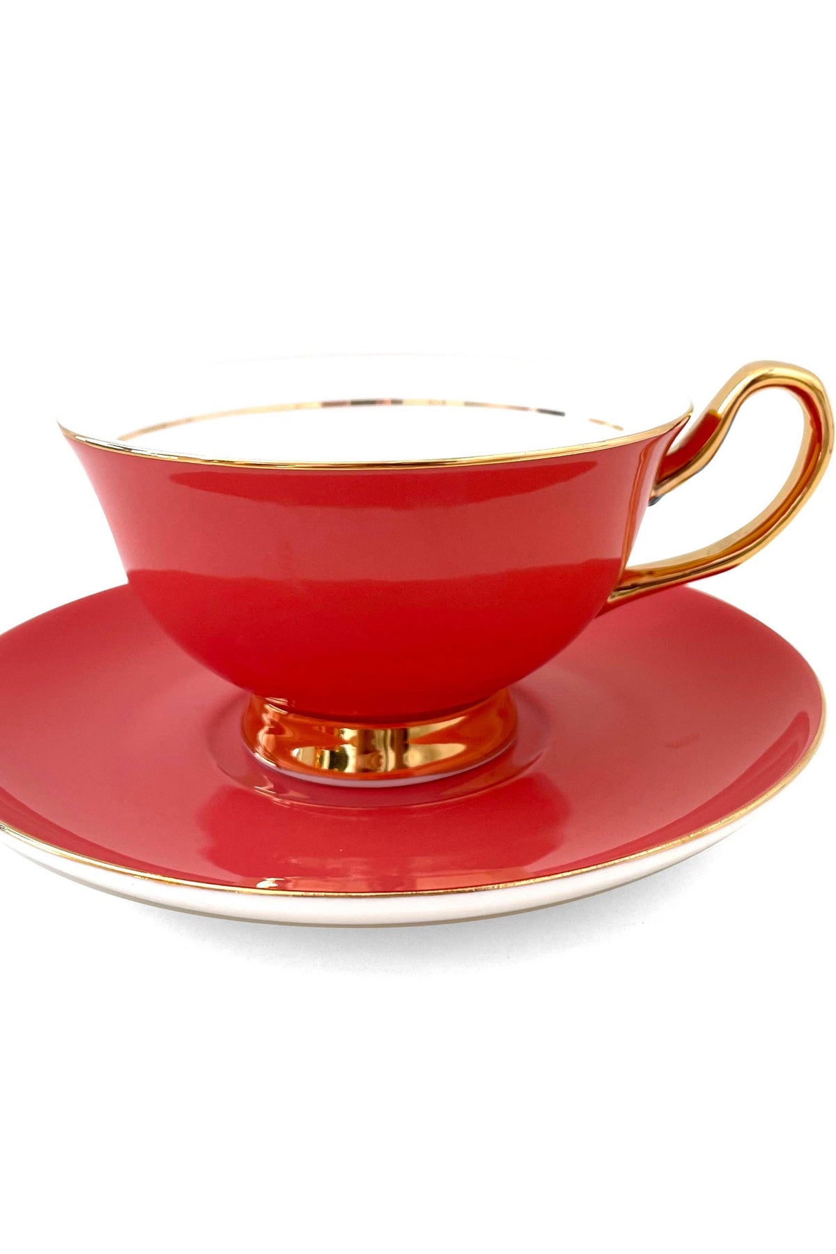Red teacup and saucer with gold trim on a white background