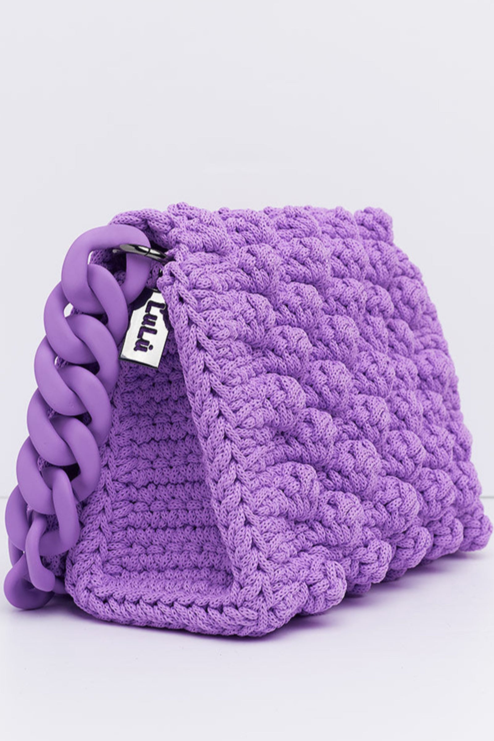 A hand made crochet bag in lilac color with a silicon chain, part of the '90s Collection'. The bag features a textured bubble pattern.