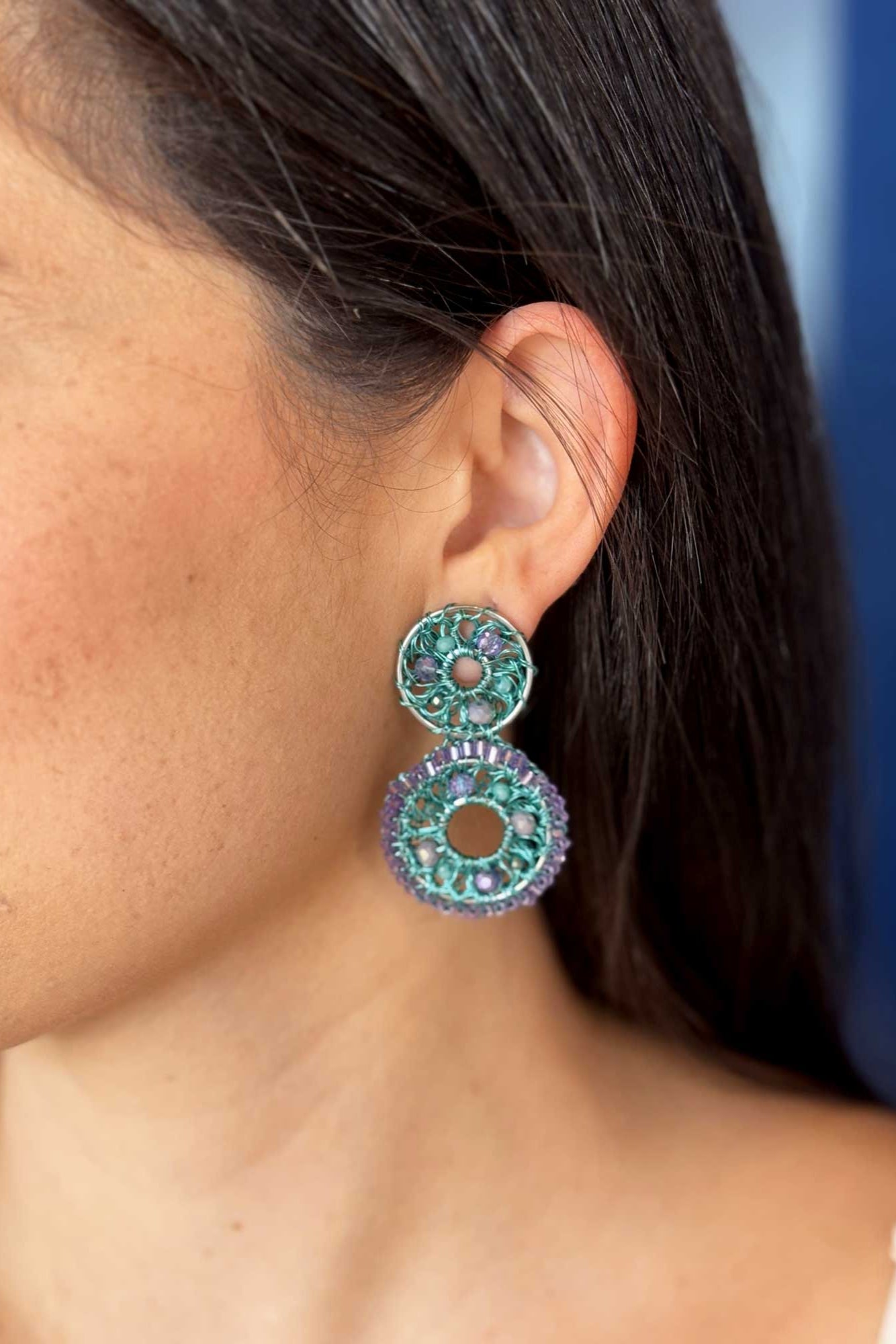 Pair of green and purple beaded earrings on a white background