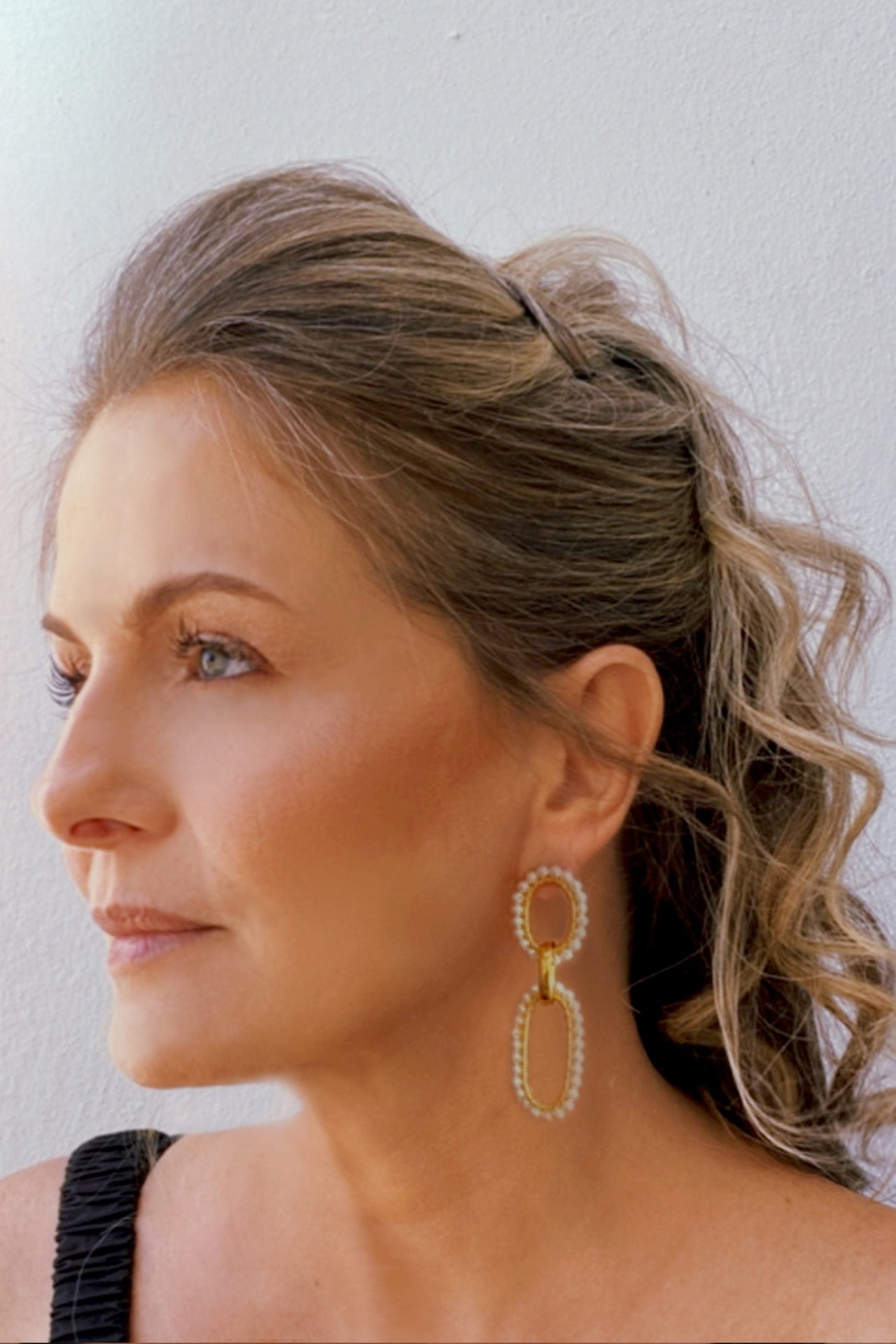 Gold and pearl earrings on a white background