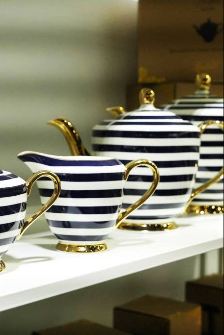 Teapot with navy and white stripes and gold accents on a white background