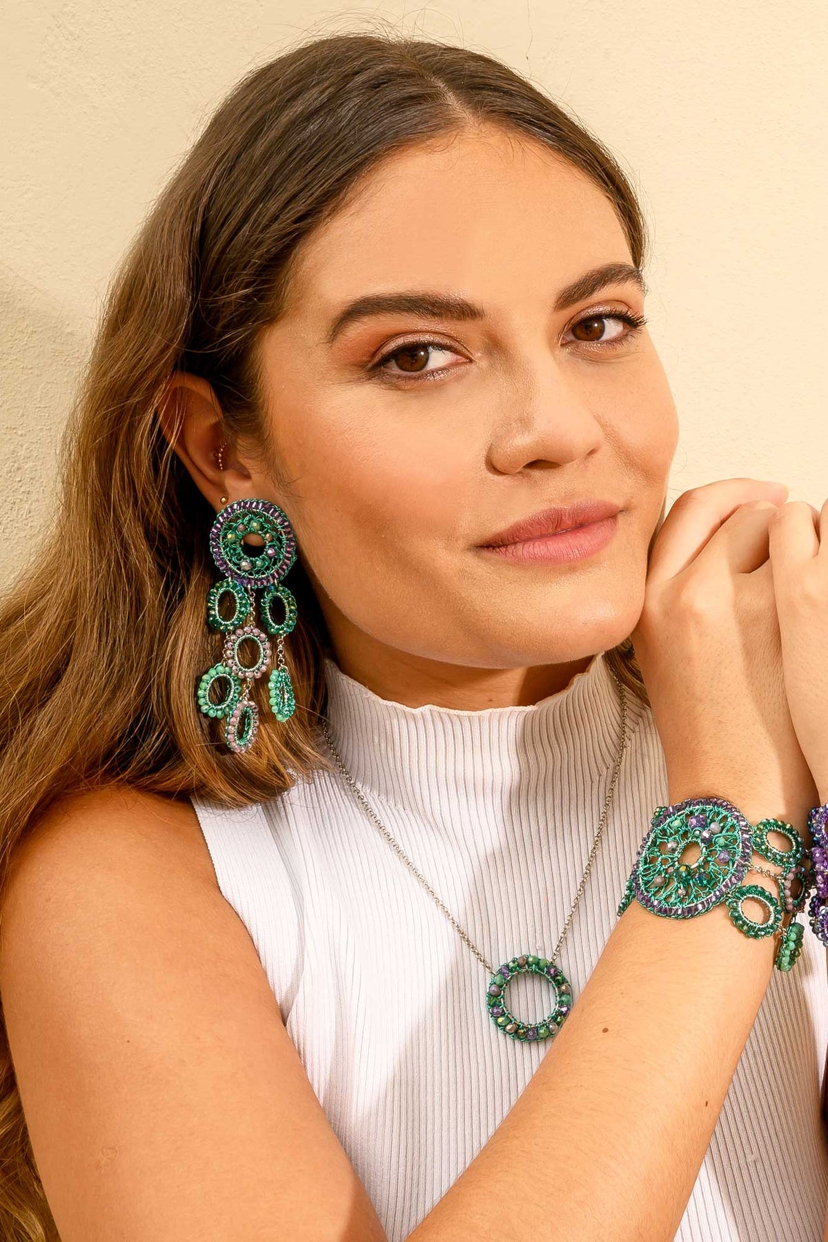 Woman wearing green and purple jewelry against a beige background