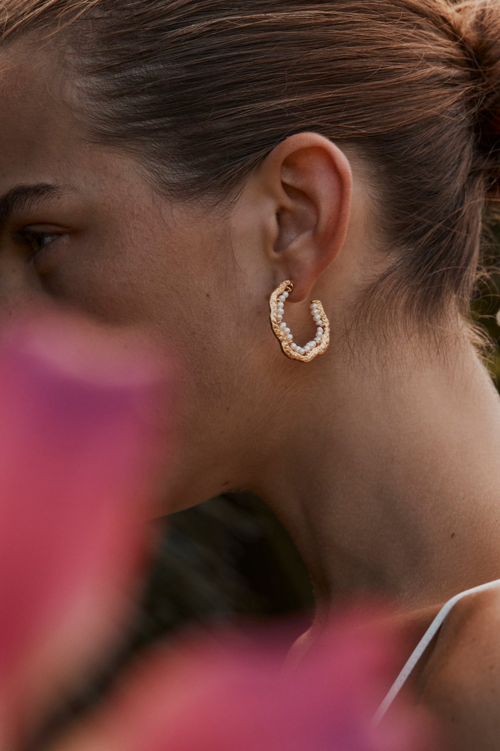A woman wearing hoop earrings with freshwater pearls.