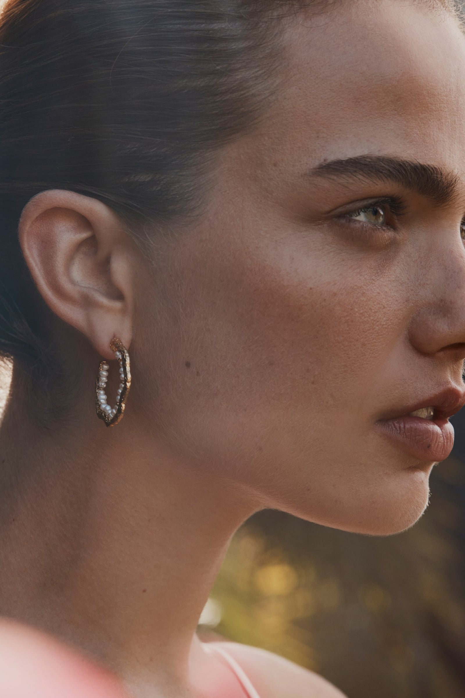 A woman wearing hoop earrings with freshwater pearls.