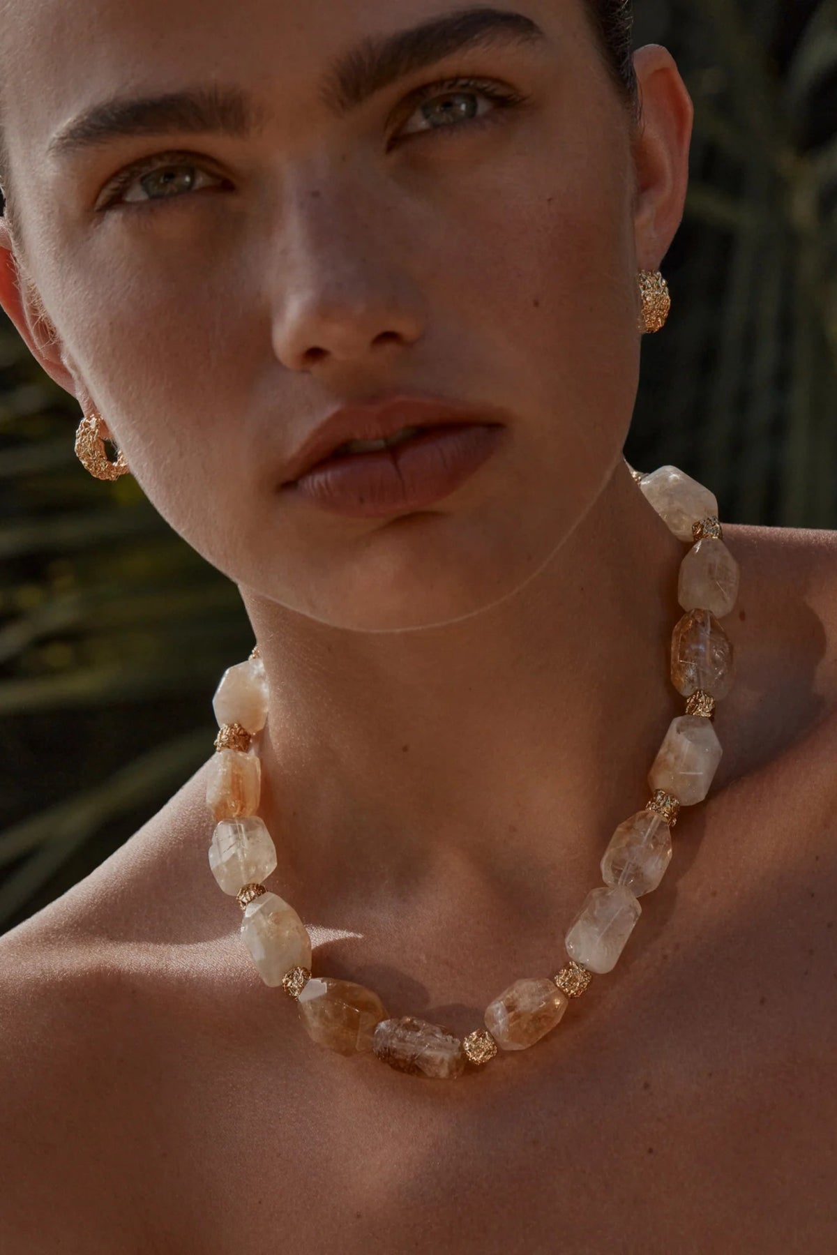 Woman wearing a necklace with a blurred natural background