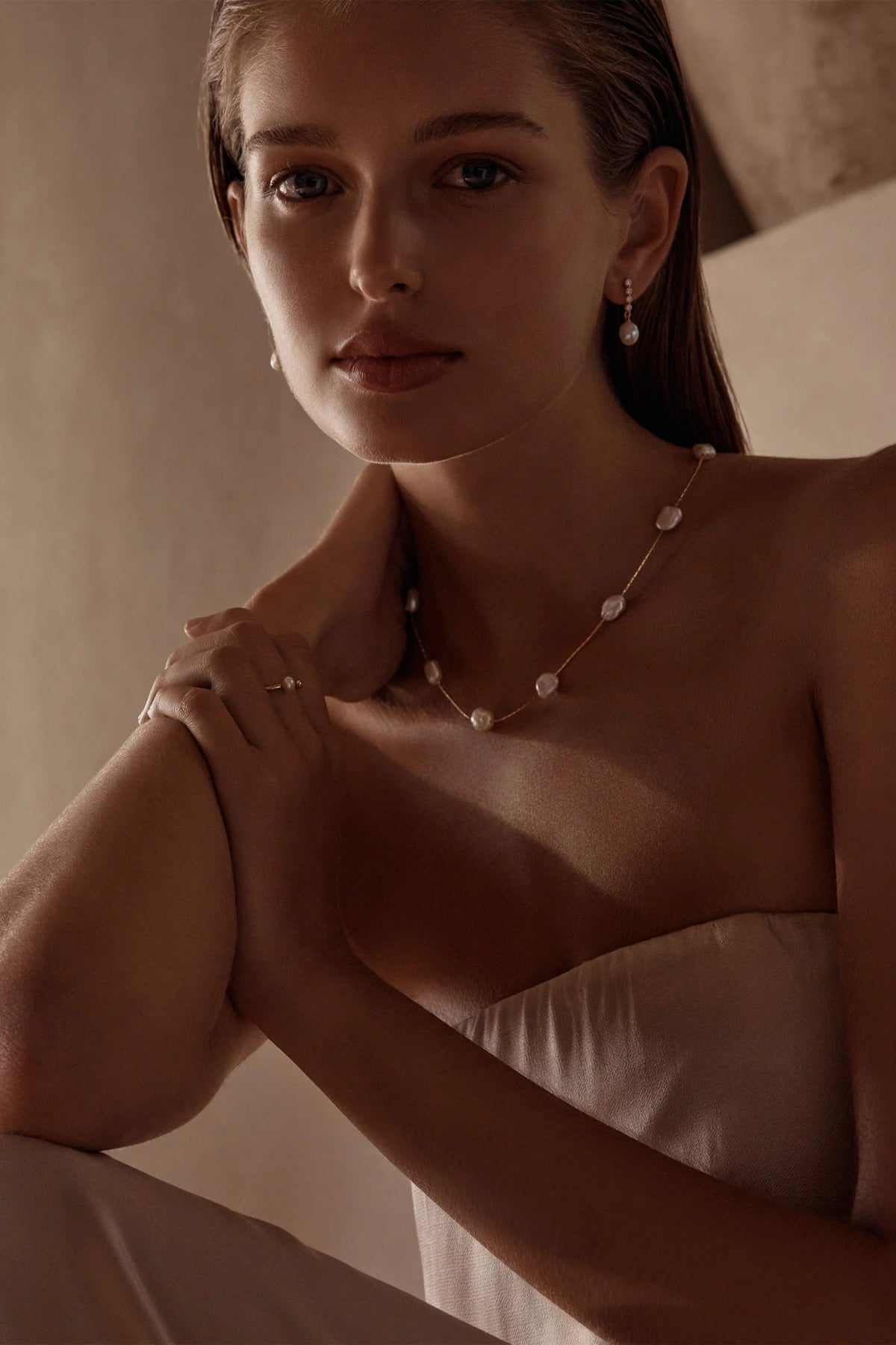 Woman wearing a delicate necklace with a neutral background
