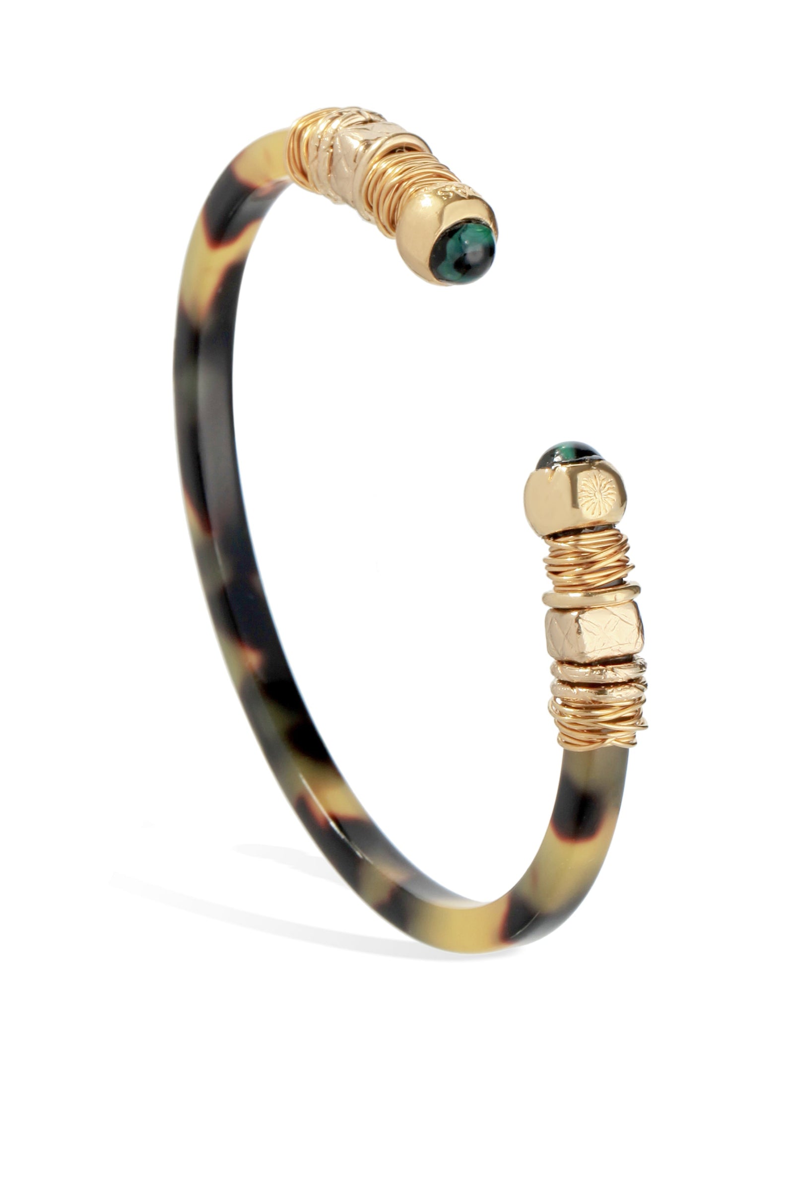 A gold-colored bracelet with a patterned strap and decorative elements, featuring small green gemstones.