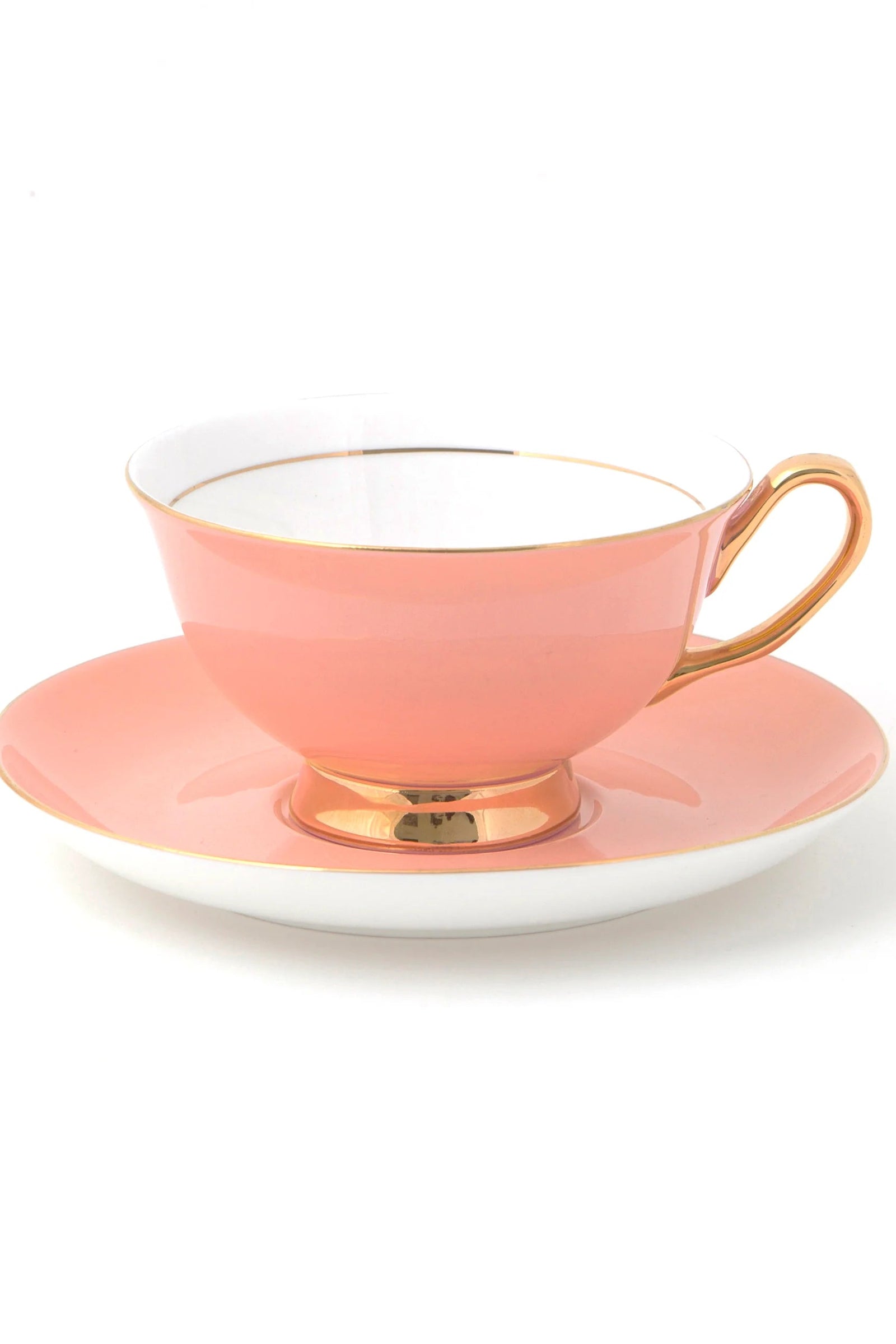 A pale pink teacup with gold trim on the rim and base, accompanied by a white saucer with a gold rim.