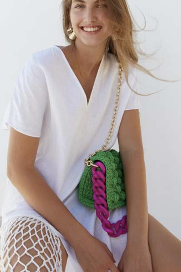 Green textured pouch with purple braided handle on a white background