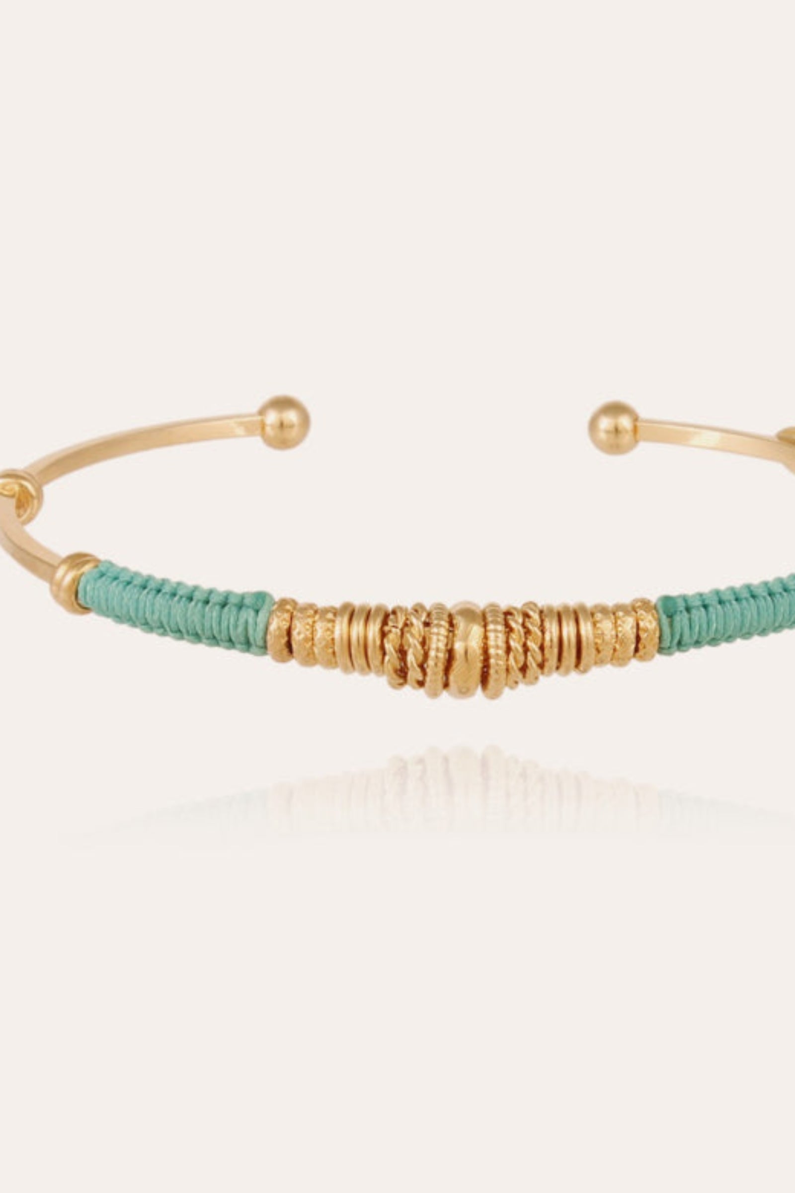 Gold plated bangle bracelet with colored threads and golden plated adornments, with an adjustable closure.