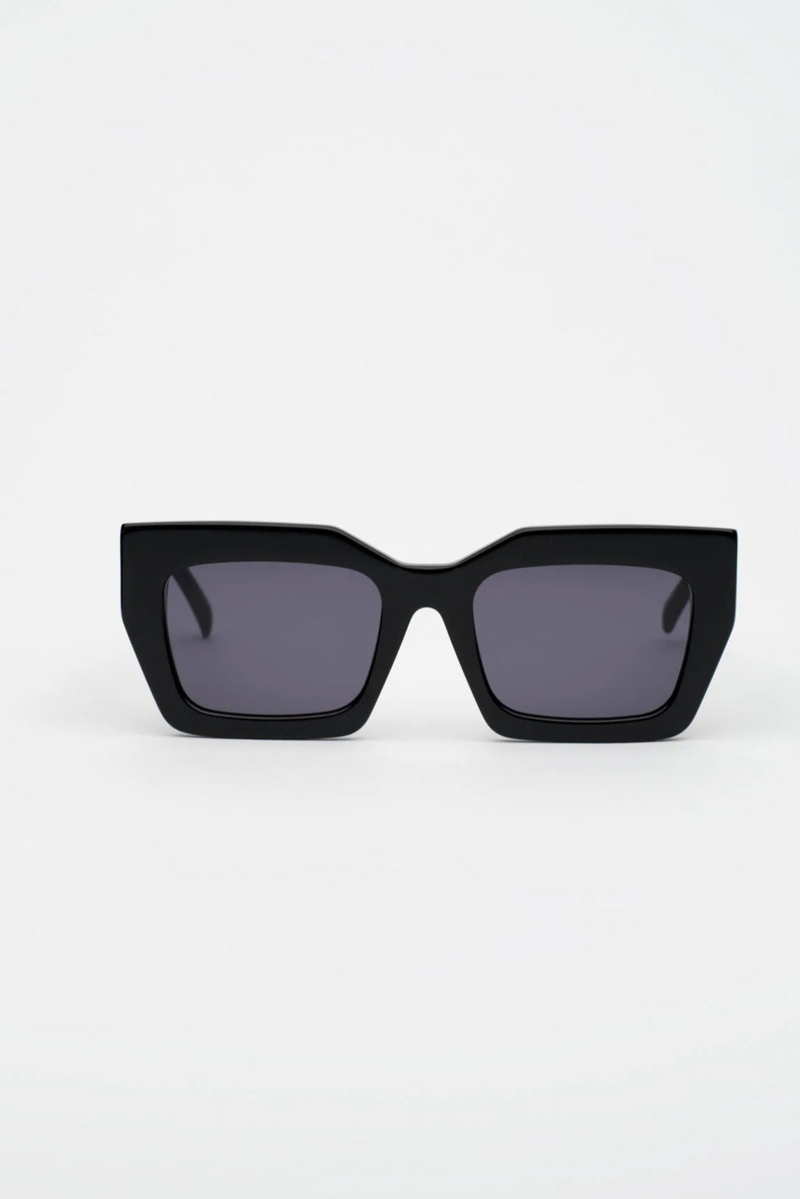 Black sunglasses with dark lenses on a light gray background