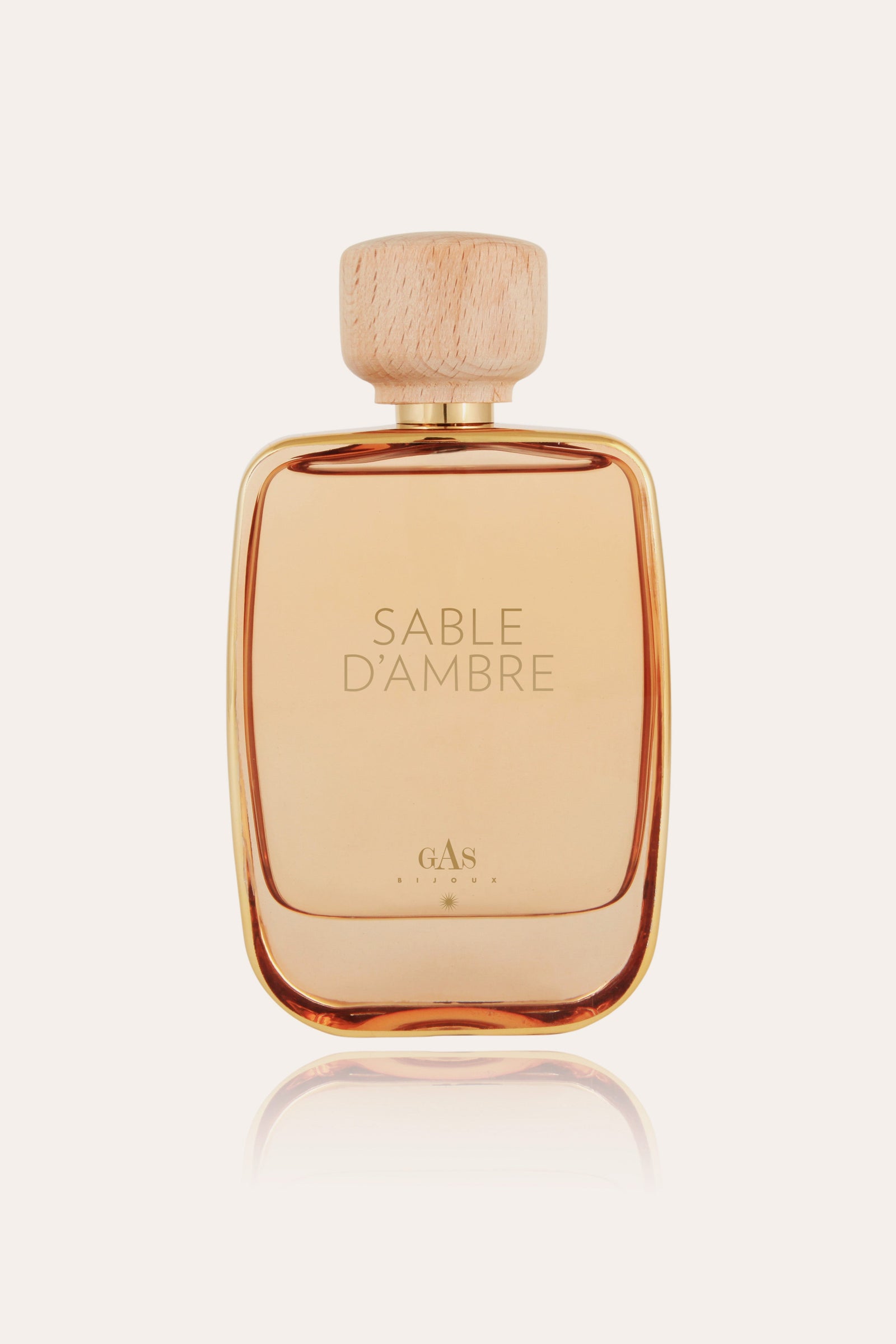Perfume bottle labeled 'Sable Dámber' on sand dunes